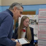 Royalmont Academy student explaining a science project to an adult during a school presentation