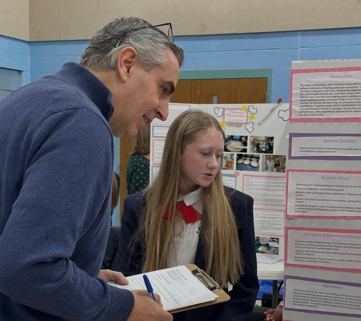 Royalmont Academy student explaining a science project to an adult during a school presentation